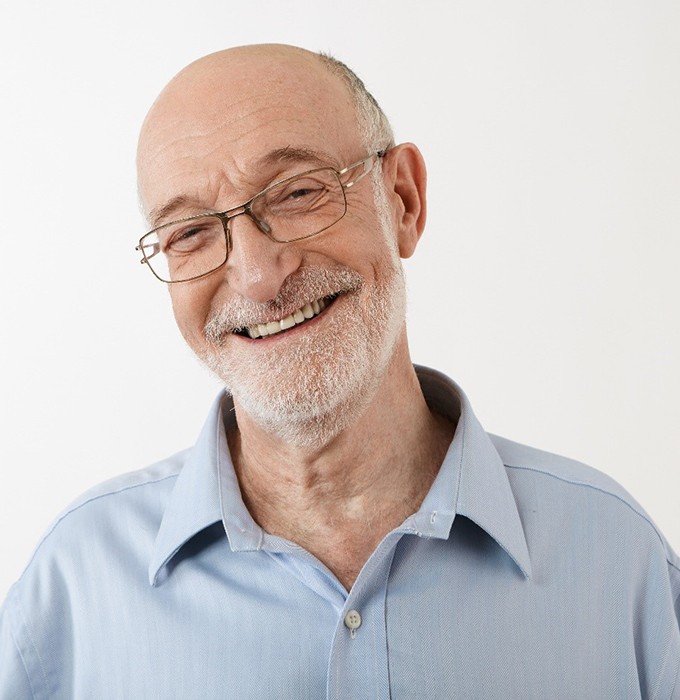 Older man in blue shirt smiling with white background