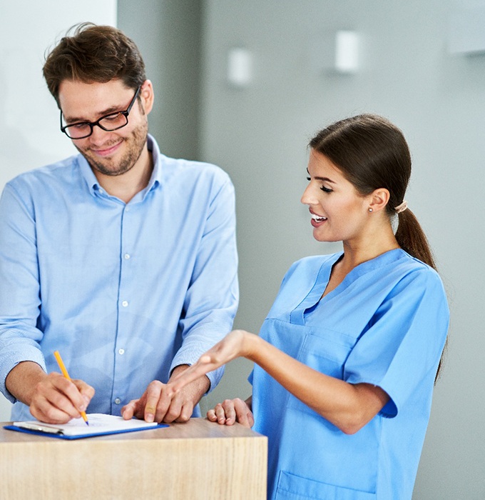 Dental team member assisting patient with paperwork