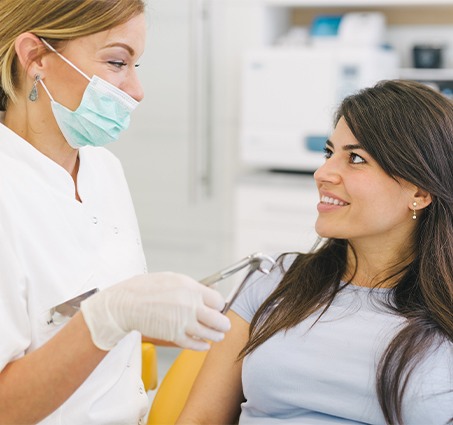 Woman smiling at dentist during tooth extraction appointment