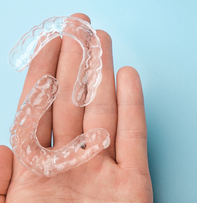 Two clear aligners resting in person’s hand