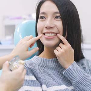 Woman pointing to her smile during implant consultation