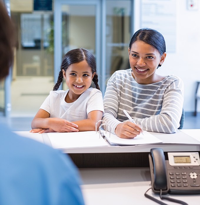 Mother and daughter checking in at dental office front desk