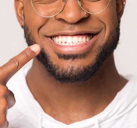 man pointing to his smile after getting dental bonding in Lansing