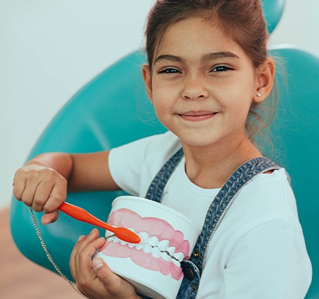 Young girl practing tooth brushing during children's dentistry visit