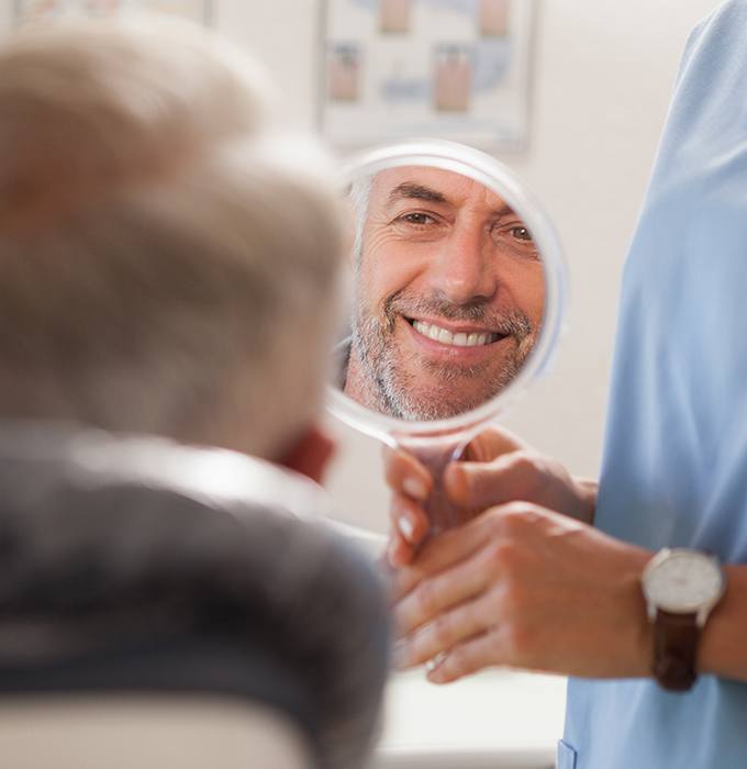 Man looking at smile after metal free dental restoration