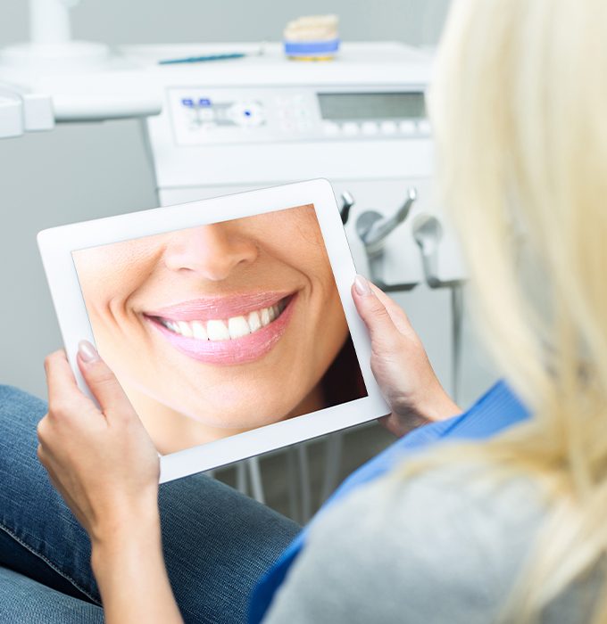 Woman looking at virtual smile design on tablet computer