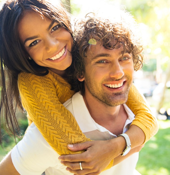 couple smiling after seeing a cosmetic dentist in Lansing