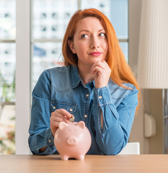 Woman putting a coin in a piggy bank