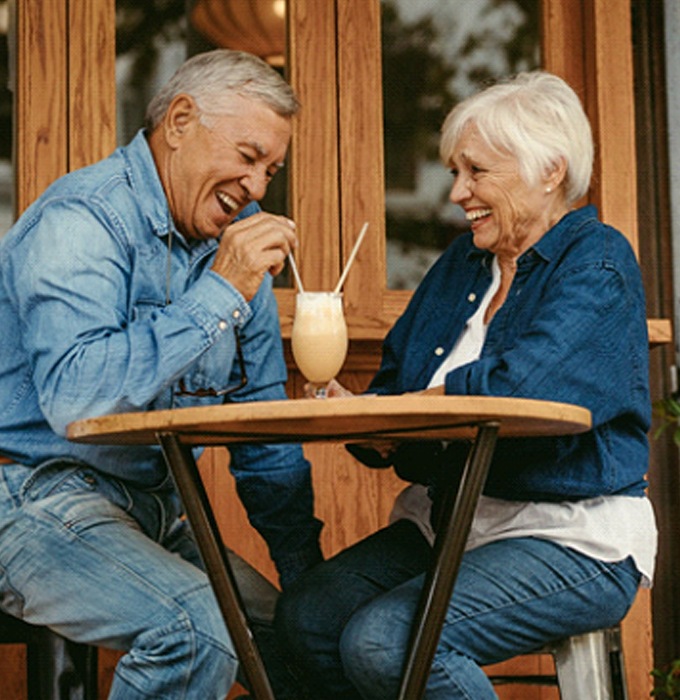 Senior couple with dentures in Lansing sharing a milkshake