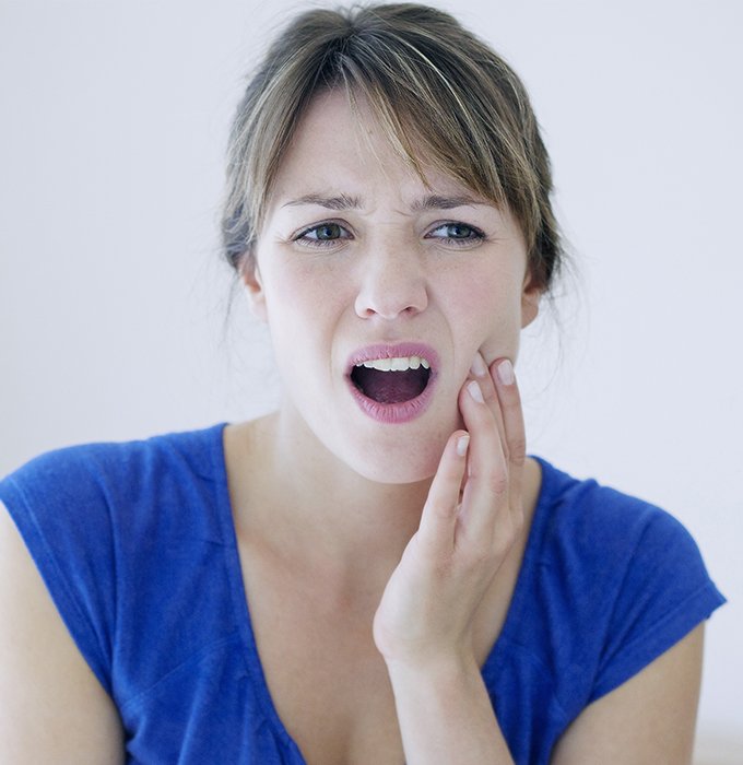 Woman in need of emergency dentistry holding cheek in pain