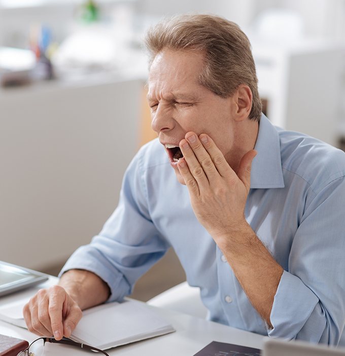 Man in need of T M J therapy holding jaw