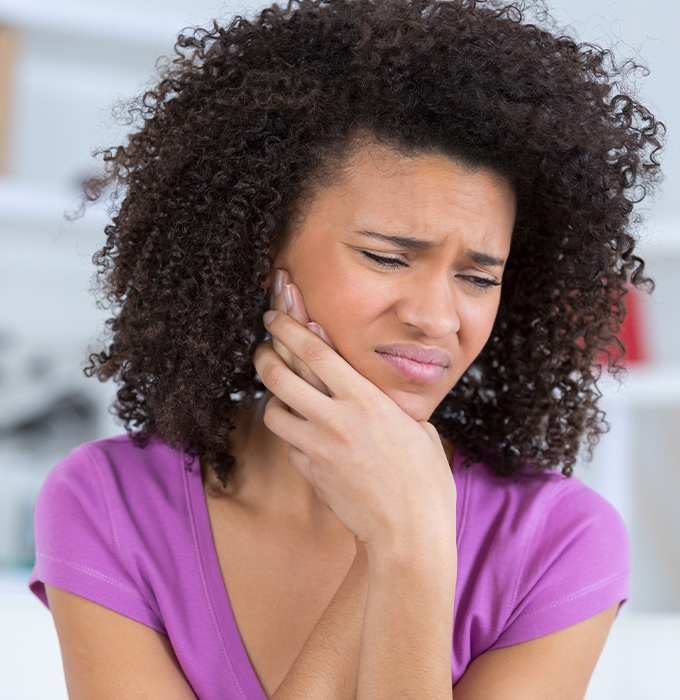 Woman in need of tooth extraction holding jaw