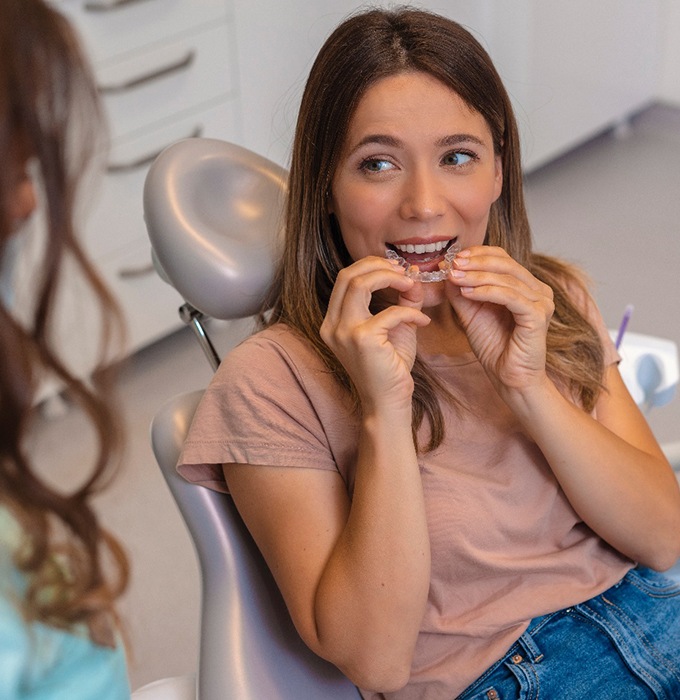 Dental patient placing clear aligner in her mouth