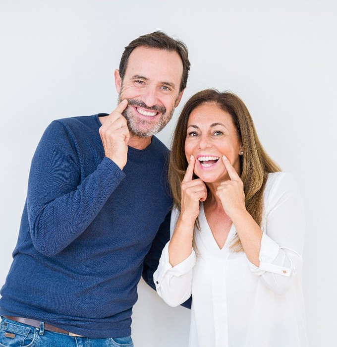 man and woman pointing to their smiles 