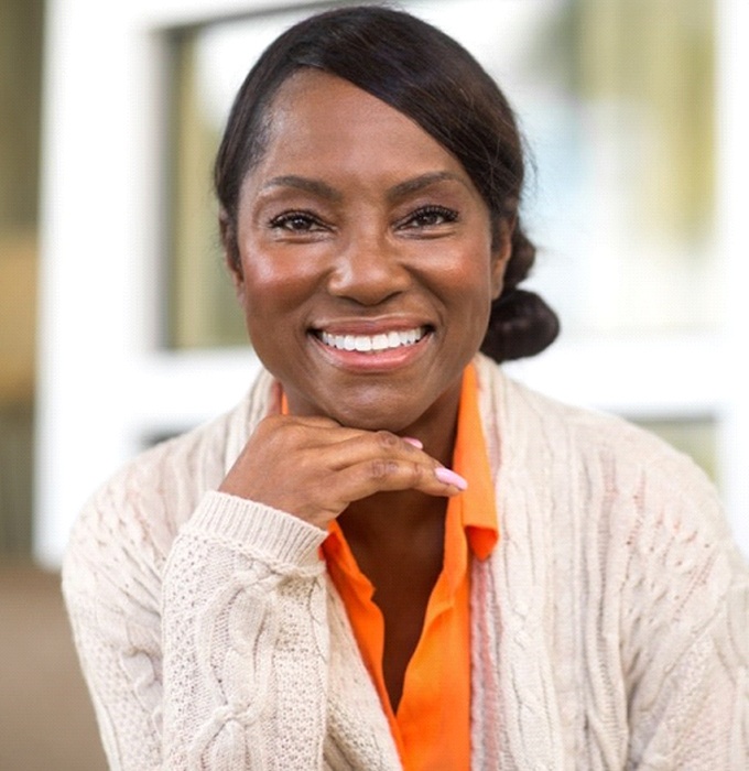 Woman wearing orange shirt and sweater smiling