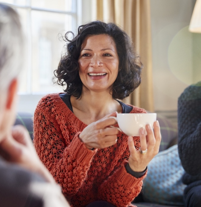Smiling woman holding coffee cup after dental implant supported tooth replacement