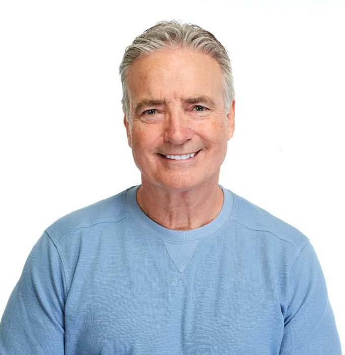 Man in blue shirt smiling with white background