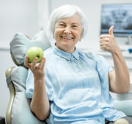 Older woman smiling after replacing missing teeth