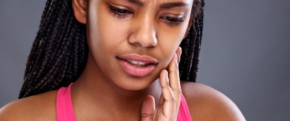 Woman in need of emergency dentistry holding jaw in pain