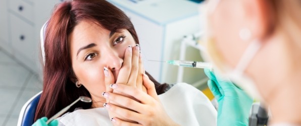 Fearful patient in need of sedation dentistry covering mouth