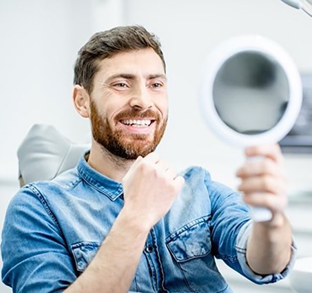 man admiring his smile with veneers in Lansing 