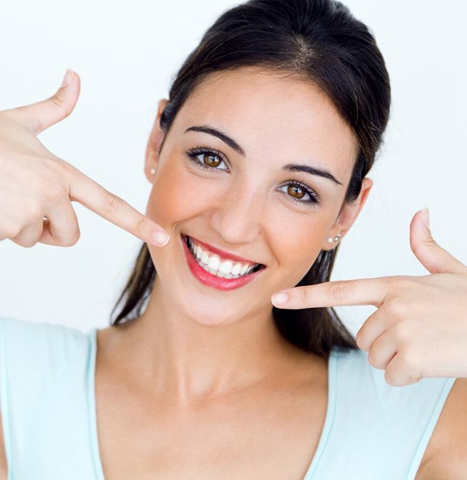 Smiling woman pointing to her white teeth