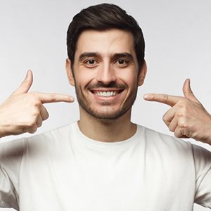 a man smiling and pointing at his newly whitened teeth