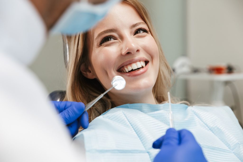 Woman smiling at dentist during biannual checkup