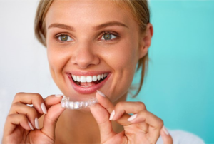 a patient smiling and holding their Invisalign aligner