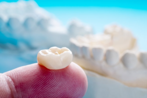 Close up of a dental crown resting on a fingertip