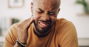 Man in pain clutching jaw. 