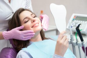 Patient smiling into mirror in dentist's chair.
